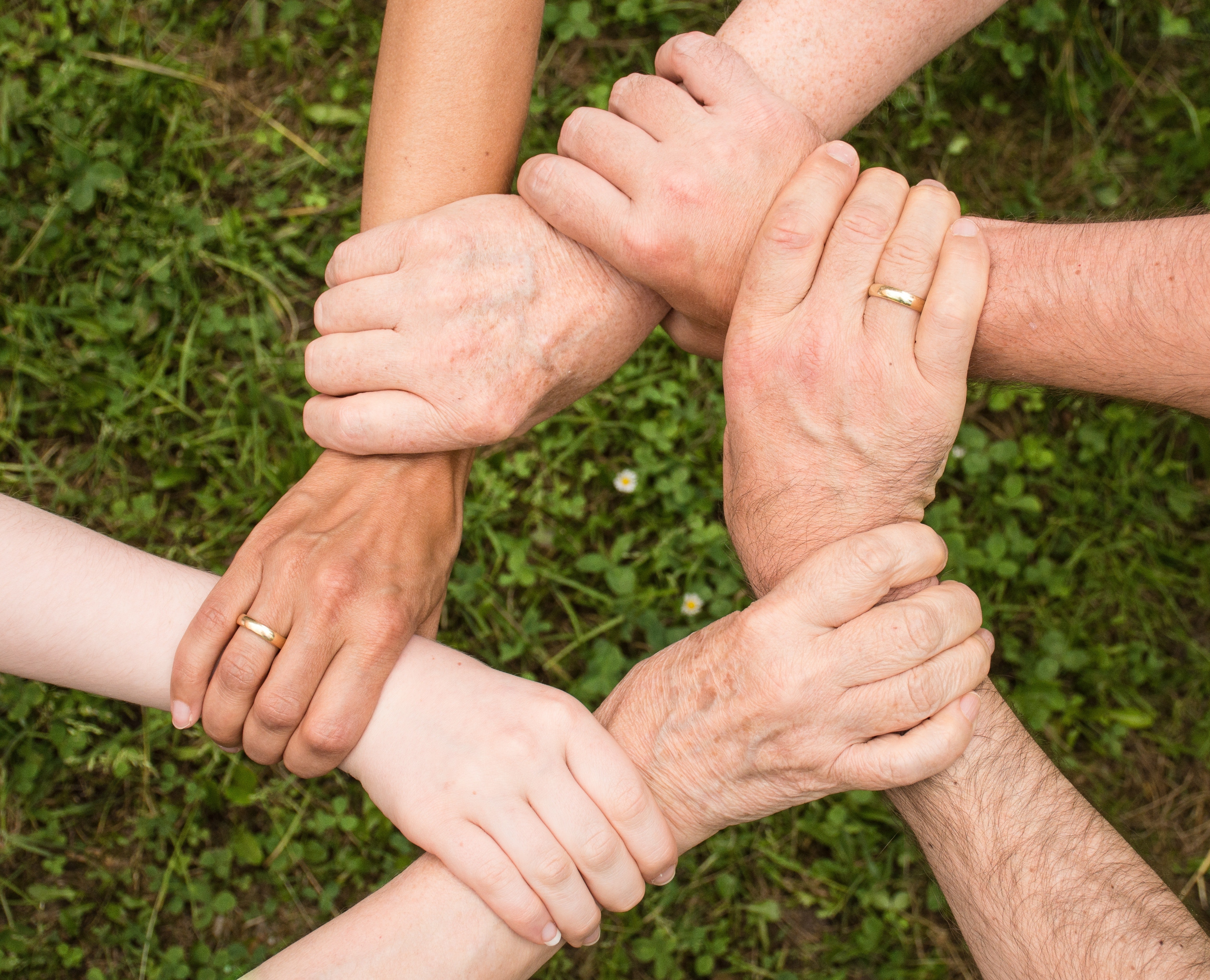 Personen halten ihre Hände aufeinander um Gemeinschaft zu symbolisieren.